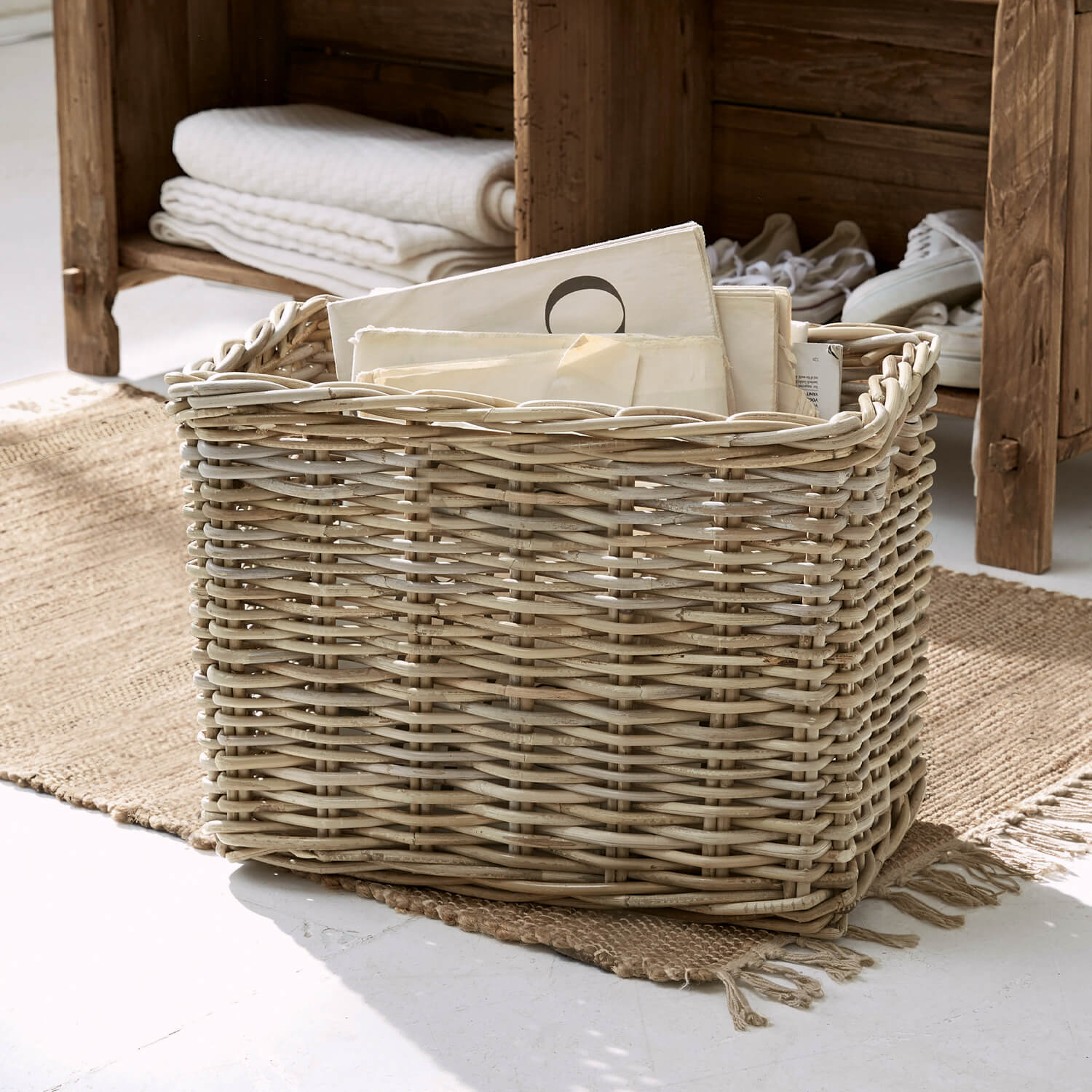 Panier en osier naturel avec documents, posé sur un tapis dans un intérieur lumineux, rangement décoratif