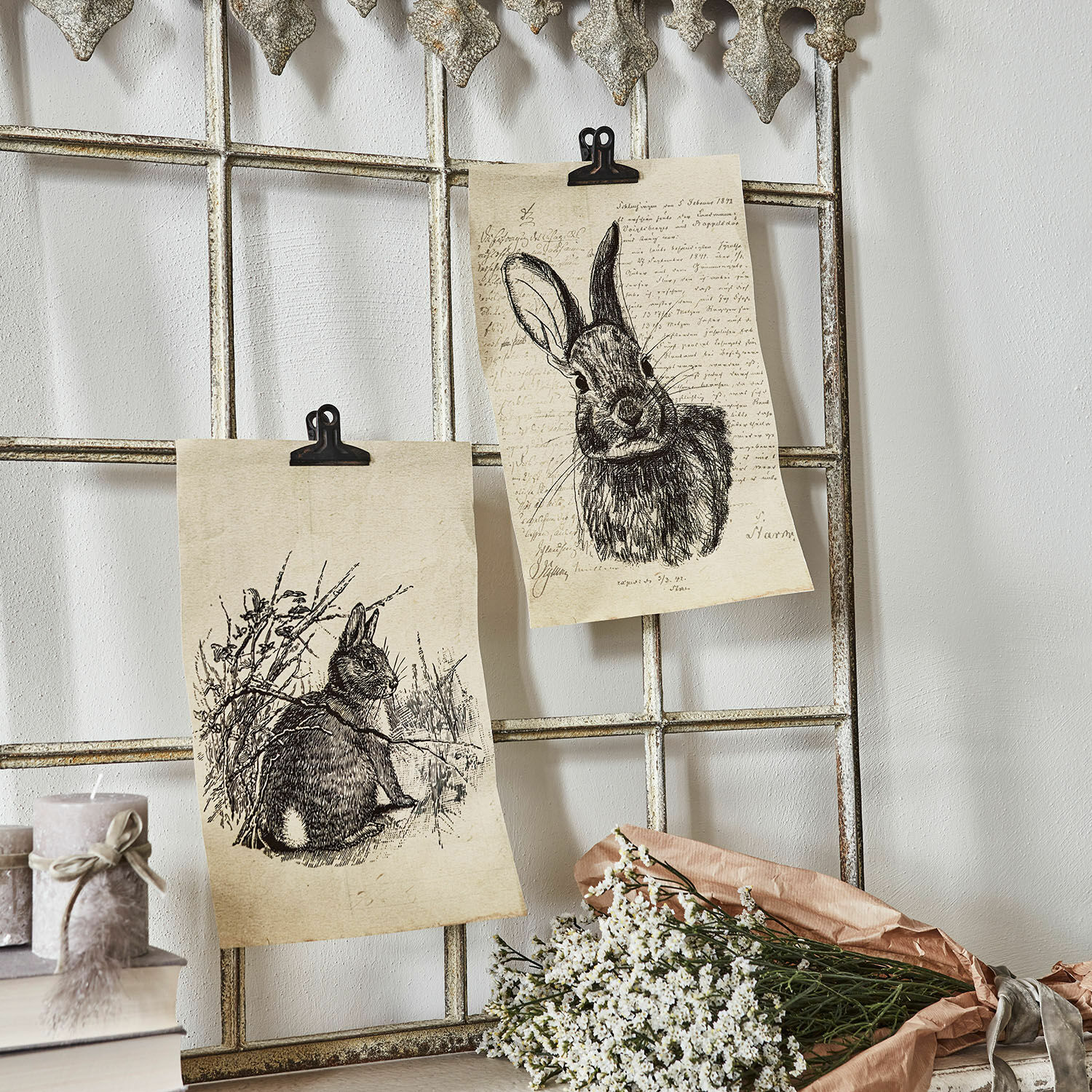 Afbeelding set van 2 Meursault Twee tekeningen van konijnen op papier bevestigd aan een metalen rooster met witte bloemen en kaarsen ernaast