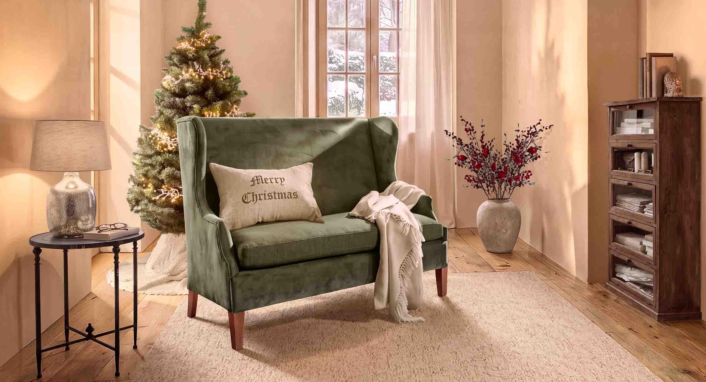 Canapé vert en velours avec coussin Merry Christmas dans un salon chaleureux décoré pour Noël