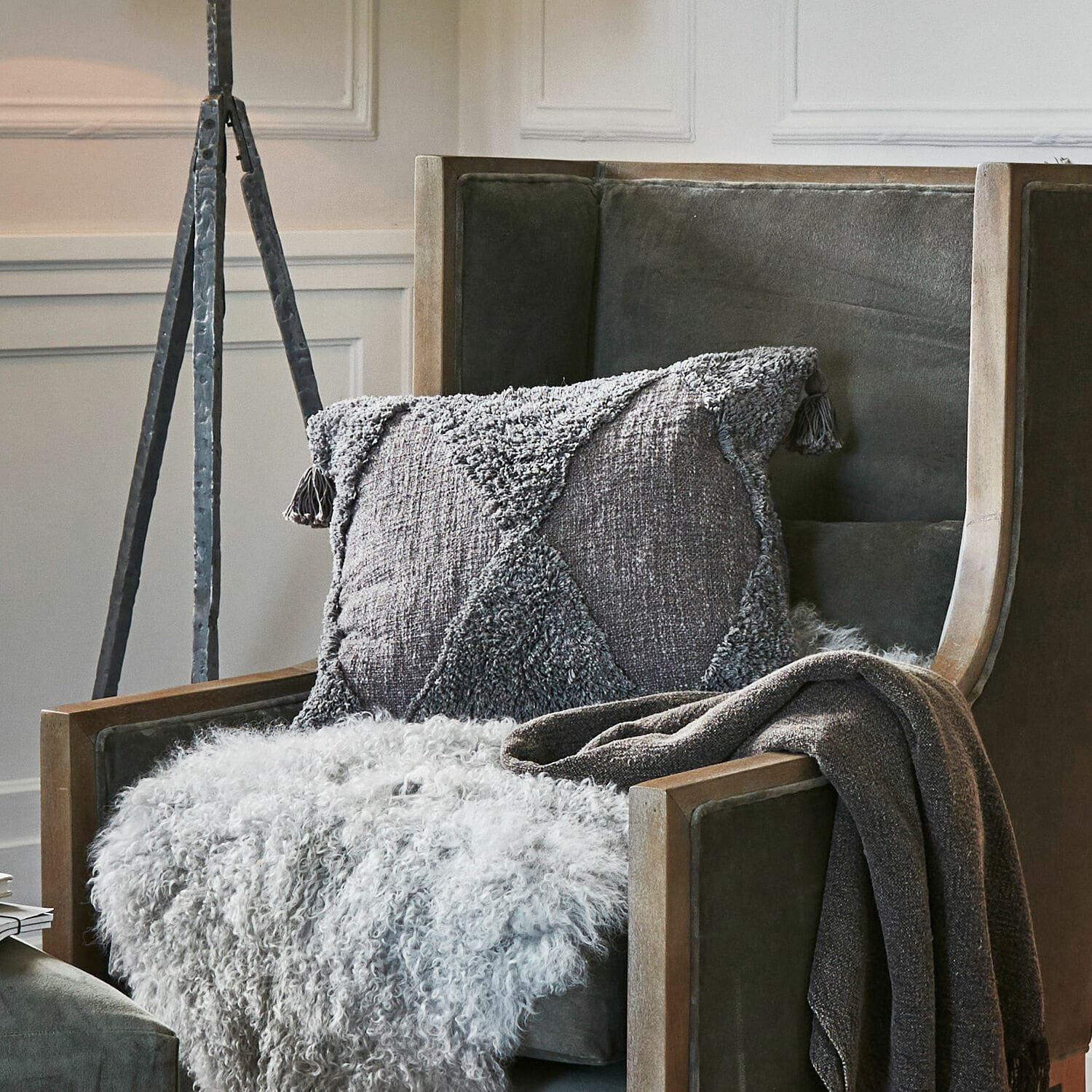 Housse de coussin Aldonsa Coussin décoratif gris et plaid doux sur fauteuil vert avec cadre en bois dans un salon élégant