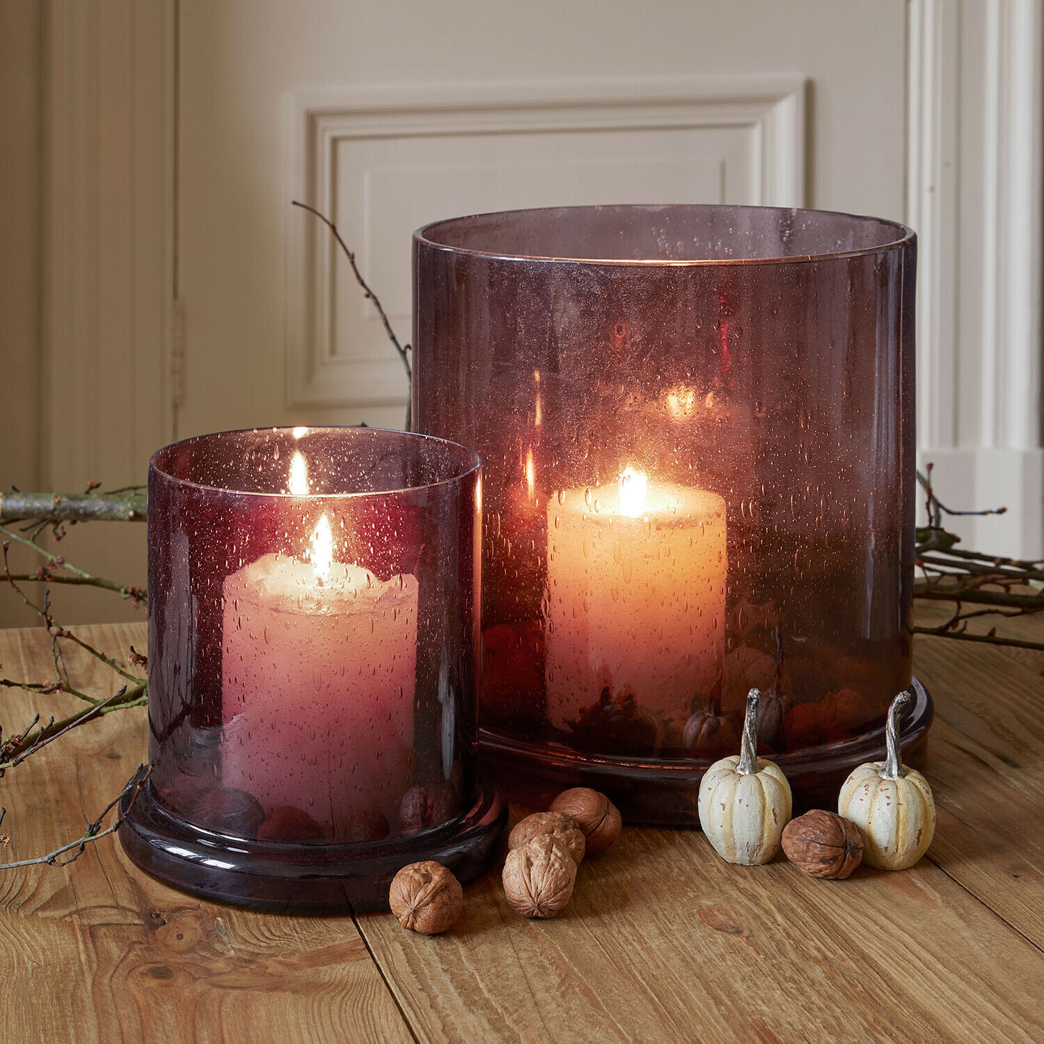 Windlicht set van 2 Saffrone Twee brandende kaarsen in paarse glazen lantaarns op houten tafel met herfstdecoratie