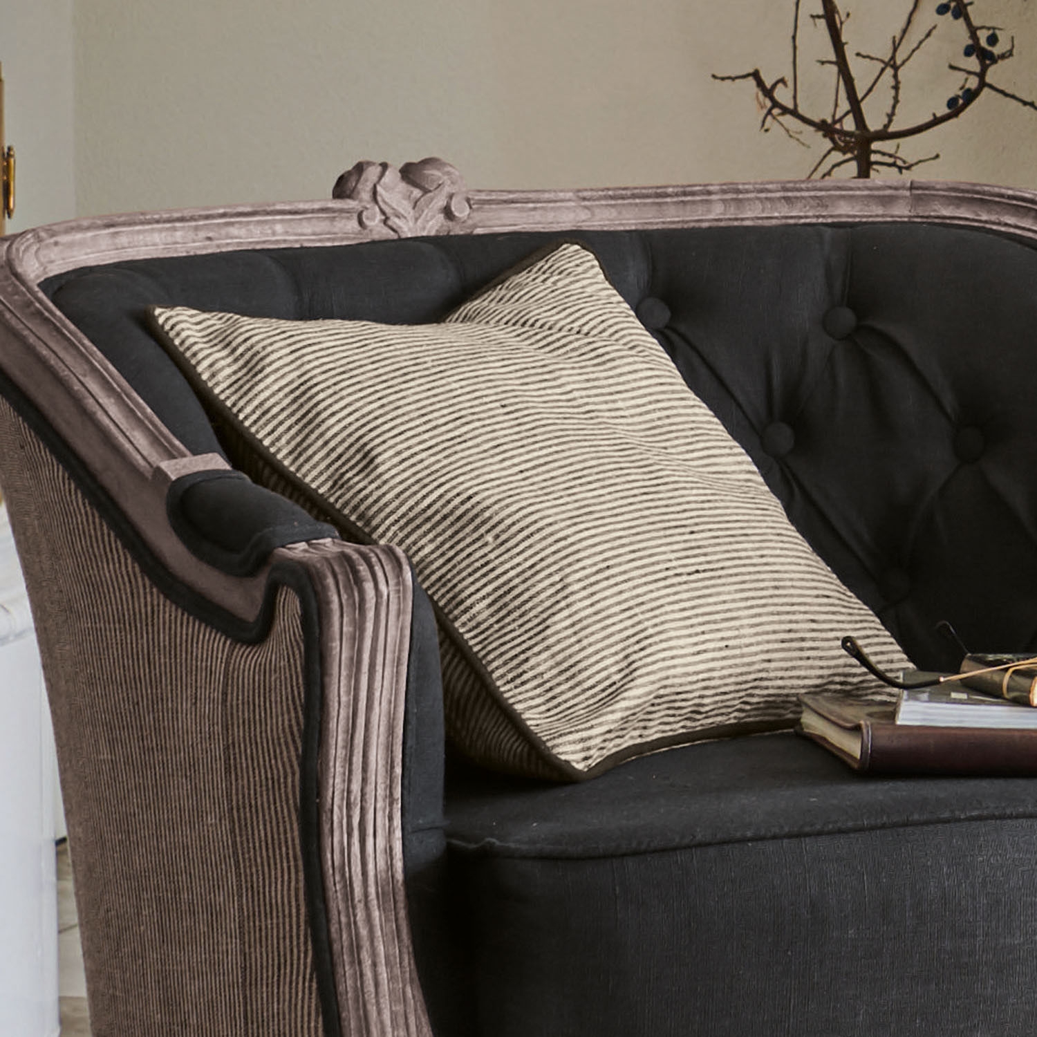 Zwarte gestoffeerde bank met beige gestreept kussen en boek, vintage stijl