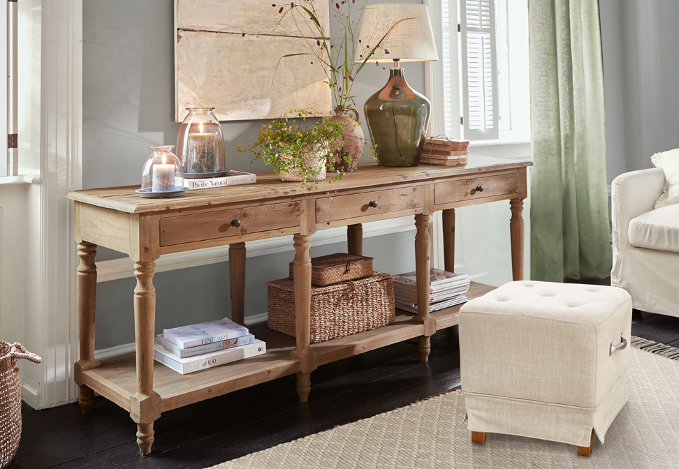 Console en bois rustique avec trois tiroirs et décorations sur le dessus dans un intérieur lumineux