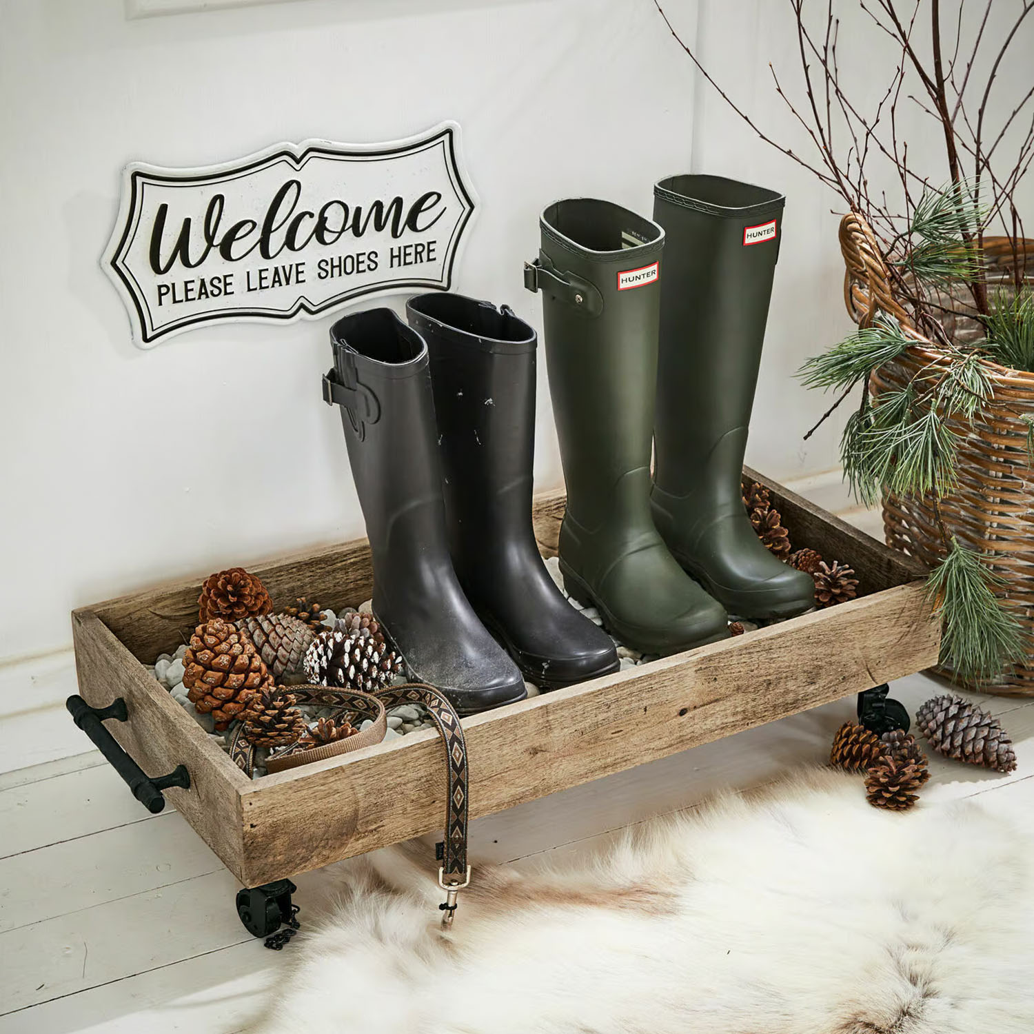 Houten dienblad op wieltjes met zwarte en groene laarzen en dennenappels in een gezellige ruimte