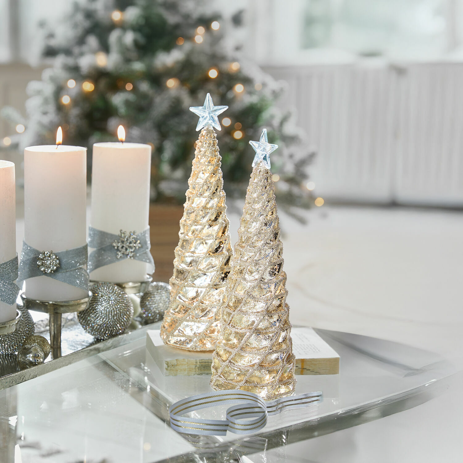 Sierboom set van 2 Glitter Twee gouden kerstboomdecoraties met sterren bovenop op glazen tafel met witte kaarsen en feestelijke achtergrond