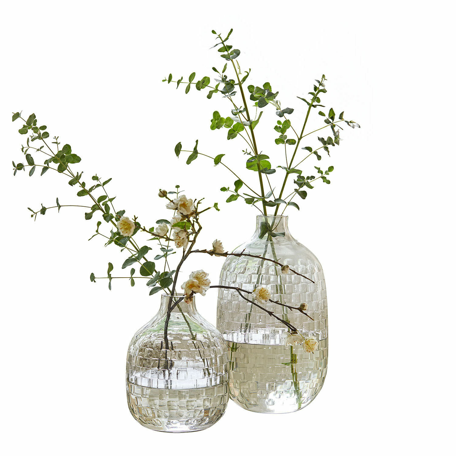 Vaas set van 2 Qervilon Twee doorzichtige glazen vazen met ruitpatroon gevuld met groene takken en witte bloemen