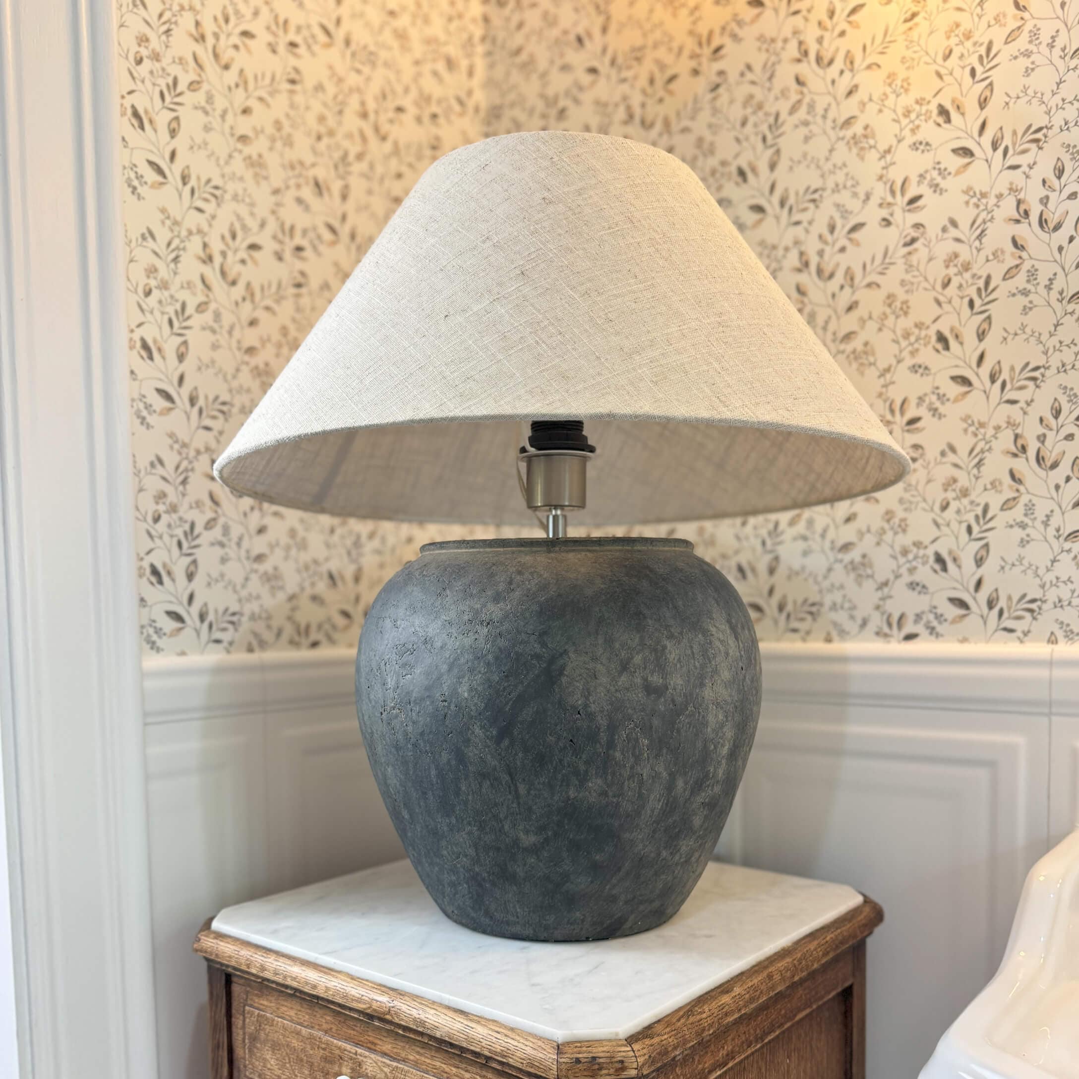 Lampe de table en céramique gris foncé avec abat-jour beige sur une table en bois dans un intérieur classique