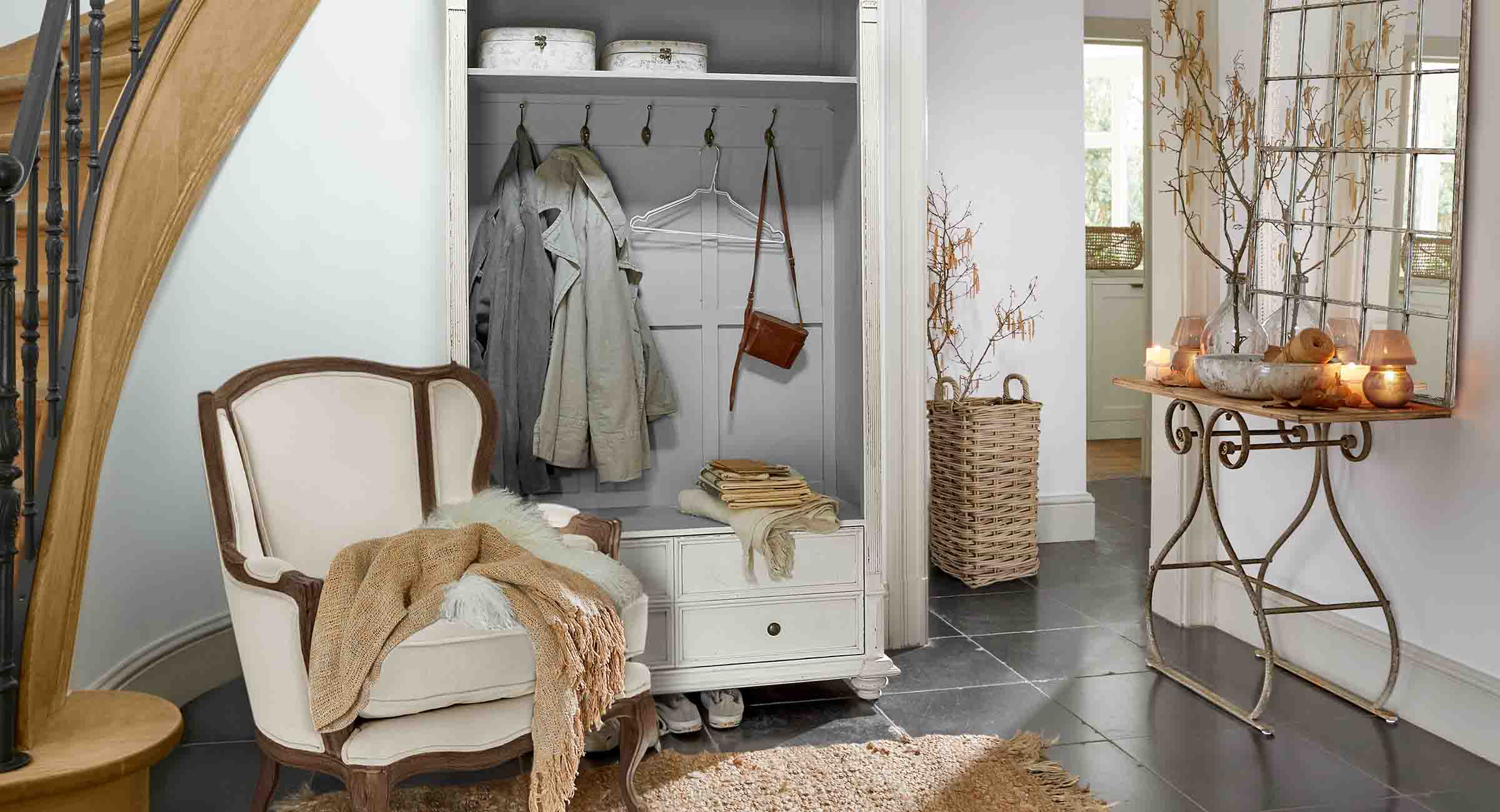Gezellige hoek met witte fauteuil, kledingkast en spiegel met metalen console in vintage stijl